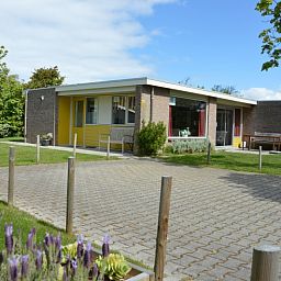 Bungalow Verste Coogh 62, Texel in De Dennen met uitnodigend terras en groene omgeving, perfect voor een rustige vakantie.