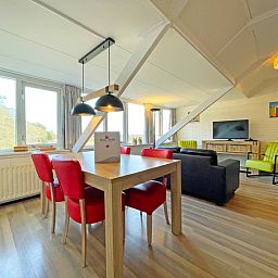 Gezellige eetruimte in Appartement Bos en Duin 36, De Dennen, Texel met houten tafel en rode stoelen.