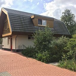 Vijverhof Ferienhaus fuer 6 Personen in De Dennen, Texel, umgeben von ueppiger Natur und mit einer einladenden Terrasse.