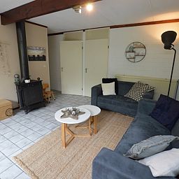 Knusse binnenruimte in Bungalow Verste Coogh 56, De Dennen, Texel, met houtkachel voor gezellige avonden.