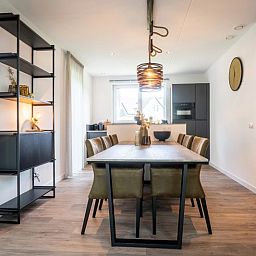 Eetkamer in Vakantiepark De Koorn-aar Villa, De Dennen Texel, met grote tafel en designverlichting.