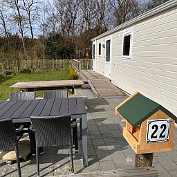 Ferienpark De Bremakker - Chalet Skeep in De Dennen, Texel, mit sonniger Terrasse und gruener Umgebung, ideal fuer einen entspannten Aufenthalt.
