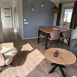 Gemuetliches Wohnzimmer im Chalet Skeep im Ferienpark De Bremakker, De Dennen, Texel. Komfortable Sitzecke und Essbereich in heller Umgebung.