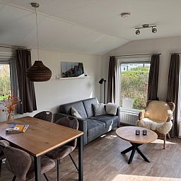 Gemuetliches Wohnzimmer im Chalet Skeep im Ferienpark De Bremakker, De Dennen, Texel. Komfortabler Sitzbereich mit Blick auf die Natur.