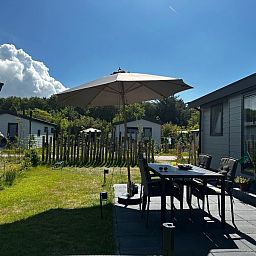 Geraeumige Terrasse mit Sonnenschirm im Vakantiepark de Bremakker - Chalet Wulk, De Dennen, Texel, ideal fuer Mahlzeiten im Freien.
