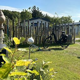 Gruener Garten mit Fahrrad im Chalet Wulk auf Vakantiepark de Bremakker, umgeben von Natur in De Dennen, Texel.