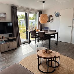 Stilvolles Wohnzimmer des Chalets Wulk im Vakantiepark de Bremakker, Texel, mit moderner Einrichtung und Gartenblick.