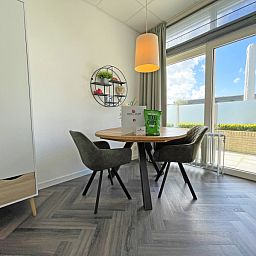 Essecke im Appartement Bos en Duin 02, De Dennen, Texel mit rundem Tisch und Blick auf die Terrasse.