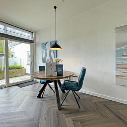 Esstisch im Apartment Bos en Duin 03, De Dennen, Texel mit Kunst an der Wand und Blick auf die Terrasse.
