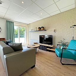 Geraeumiges Interieur des Apartments Bos en Duin 16 in De Dennen Texel mit Blick auf die gruene Umgebung.