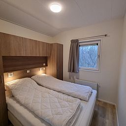 Sfeervolle slaapkamer met tweepersoonsbed in Vakantiepark de Bremakker, Weideveld 75, Texel, omringd door natuur.