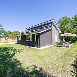 Zijaanzicht van Tormentil vakantiewoning in De Dennen, Texel met groene omgeving.