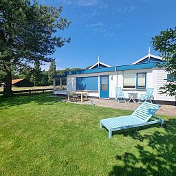 Veranda of Weidezicht vacation home in De Dennen, Texel with deck chair and garden.