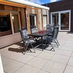 Sonnige Terrasse am Ferienhaus Hesselte in De Dennen, Texel mit Gartentisch.