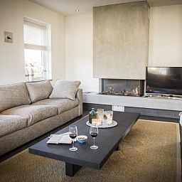 Gemuetliches Wohnzimmer in der Villa bij Zee, Bungalowpark 't Hoogelandt, Texel. Gemuetliche Sitzecke mit Kamin und Blick auf De Dennen.