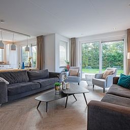 Gemuetliches Wohnzimmer in der Villa Bloem en Bos, Bungalowpark 't Hoogelandt, De Dennen, Texel, mit bequemen Sofas und Blick auf den Garten.
