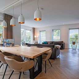 Geraeumiger offener Wohnraum in der Villa Bloem en Bos, Bungalowpark 't Hoogelandt, De Dennen, Texel, mit Zugang zum Garten und Essbereich.