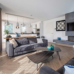 Open keuken en zitgedeelte in Villa Menno, Bungalowpark 't Hoogelandt, Texel, met comfortabele bank.