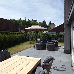 Uitzicht op het groene terras van Vakantiehuis Gortersmient 322 in De Dennen, Texel, met moderne tuinmeubels.