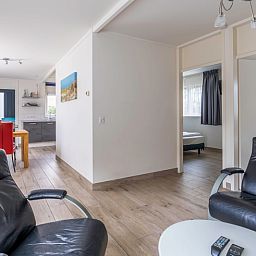 Open leefruimte in Bungalowpark 't Luwe Land, Texelfan, De Dennen, Texel. Ruime woonkamer met toegang tot de slaapkamer in de vakantiewoning.