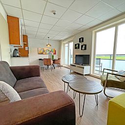 Helles Wohnzimmer des Appartements Bos en Duin 19, Texel mit gemuetlicher Sitzecke und grossen Fenstern.