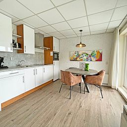 Kompakte Kueche im Appartement Bos en Duin 19, De Dennen, Texel mit Essecke und farbenfroher Malerei.