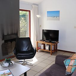 Gemuetliches Wohnzimmer mit Kamin im Ferienhaus Gortersmient 260, De Dennen, Texel, ideal zum Entspannen.