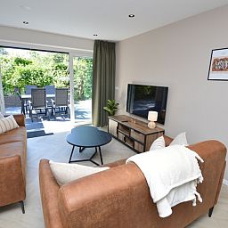 Geraeumiges Wohnzimmer des Bungalows 't Hoogelandt 58, Texel, mit Zugang zur sonnigen Terrasse.