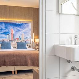 Gezellige slaapkamer in Hotel Milano, vakantieappartement in Rotterdam, met kunstwerk en moderne voorzieningen.