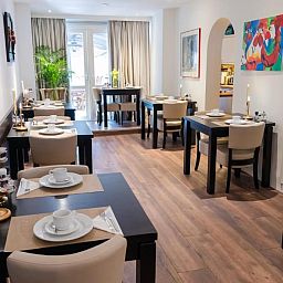 Gemuetlicher Essbereich im Hotel Orion, Ferienwohnung in Rotterdam, Suedholland mit Tischen und Stuehlen.