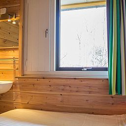 Knusse slaapkamer met houten interieur in Villabungalow, vakantiehuis in Oosterend, Terschelling, ideaal voor een ontspannen verblijf op de Waddeneilanden.
