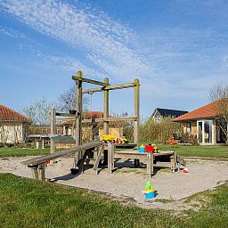Speeltuin met zandbak bij Villabungalow, vakantiehuis in Oosterend, Terschelling, perfect voor kinderen in de natuurlijke omgeving van de Waddeneilanden.