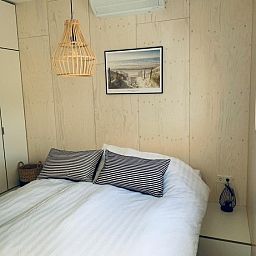 Attractive bedroom in vacation home Kleine Walvis, Midsland Noord, Terschelling with double bed and art on the wall.