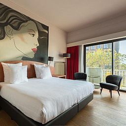 Luxe slaapkamer in Apollo Hotel Utrecht City Centre met balkon en uitzicht op Utrecht, ideaal voor een ontspannen verblijf.