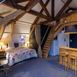 Ruime slaapkamer in Hotel Museumkwartier Utrecht, vakantie appartement met houten balken en gezellige sfeer.