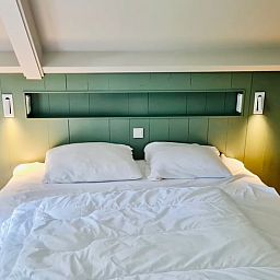Attraktives Schlafzimmer im Ferienhaus in Ballum, Ameland mit komfortablem Bett und sanfter Beleuchtung fuer eine gute Nachtruhe.