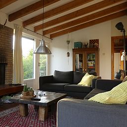 Cozy living room in Jans vacation home, Ballum, Ameland, with fireplace and wooden beams.