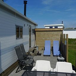 Spacious terrace at Eilandgeluk chalet in Ballum, Ameland, with deck chairs and views of the Wadden Islands nature.