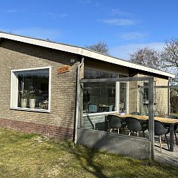 Moderne glazen veranda bij Zeevonk vakantiehuis in Ballum, Ameland, omgeven door natuur op de Waddeneilanden.