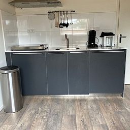 Kompakte Kueche einer kleinen Wohnung in Ballum, Ameland, mit moderner Ausstattung und Holzboden.