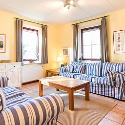 Gezellige woonkamer in Engelsmanduinvilla 8, een bungalow in Hollum, Ameland, met comfortabele banken en veel natuurlijk licht.