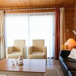 Gemuetliches Wohnzimmer des FINSE BUNGALOW 4 in Hollum, Ameland, mit bequemer Sitzecke und viel Tageslicht.