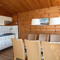 Esszimmer und Kueche des FINSE BUNGALOW 4 in Hollum, Ameland, mit hoelzernem Interieur und modernen Annehmlichkeiten.