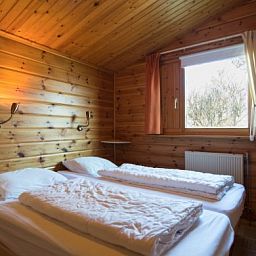 Schlafzimmer im FINSE BUNGALOW 4, Hollum, Ameland, mit gemuetlicher Holzeinrichtung und Blick auf die Natur.