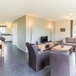 Spacious living room of ENGELSMANDUINVILLA DELUXE 6 vacation home in Hollum, Ameland with modern decor and lots of natural light.