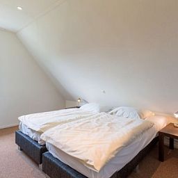 Cozy bedroom in ENGELSMANDUINVILLA DELUXE 6 vacation home in Hollum, Ameland with comfortable beds for a good night's sleep.