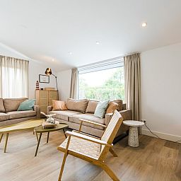 Gezellige woonkamer van Finse Bungalow Luxe 8 in Hollum, Ameland, met moderne inrichting en uitzicht op de natuurlijke omgeving.