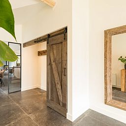 Innenraum mit Holzschiebetuer und Spiegel im Bungalow Wagenschuur, Hollum, Ameland, Watteninseln.