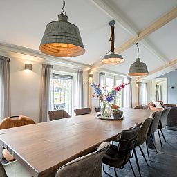 Gemuetliches Esszimmer im Bungalow Wagenschuur, Hollum, Ameland mit langem Tisch und Blick auf die Natur.