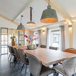 Heller Essbereich im Ferienhaus Wagenschuur, Hollum, Ameland mit grossen Fenstern und moderner Beleuchtung.